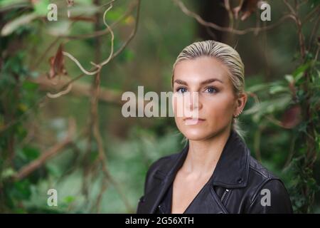 Moda in luoghi insoliti, giovane donna in giacca Edgy Moto nella foresta Foto Stock