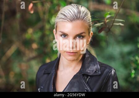 Moda in luoghi insoliti, giovane donna in giacca Edgy Moto nella foresta Foto Stock