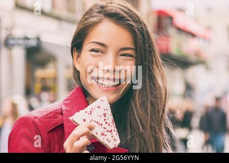 Donna asiatica che mangia biscotti in città strada felice sorridente. Ragazza con una torta di lamponi hindbaersnitte godendo dello stile di vita urbano. Danimarca viaggio turistico Foto Stock