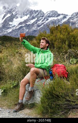 tramper kiwi della Nuova Zelanda scattare foto selfie del telefono durante l'escursione sulla pista di Hooker Valley a Mt Cook. Estate escursionista mangiare pausa pranzo durante Foto Stock