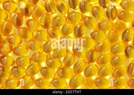 Le capsule di vitamina D si avvicinano a uno sfondo giallo su una cornice completa. Concetto di industria farmaceutica. Foto Stock