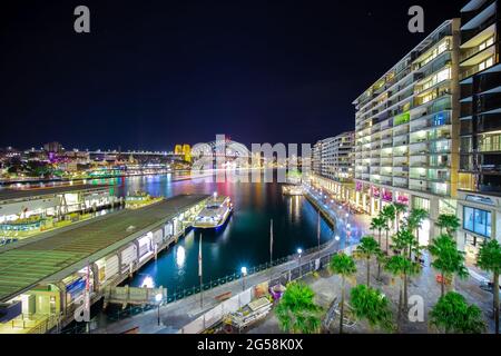 Vista panoramica notturna del porto di Sydney e dello skyline della città di Circular Quay, il ponte nsw Australia. Luminose luci al neon che si riflettono sull'acqua e Foto Stock