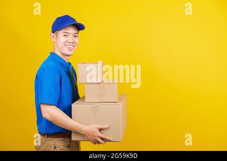 Ritratto eccitato attraente consegna felice uomo logistico sorriso in piedi indossando t-shirt blu e tappo uniforme contenitore di tenuta pacchi guardando fotocamera, prigioniero Foto Stock