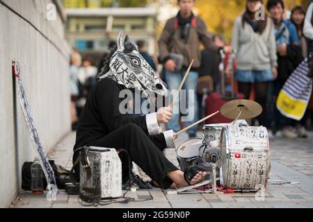 Un uomo che busking mentre indossa una maschera a Tokyo, Giappone Foto Stock