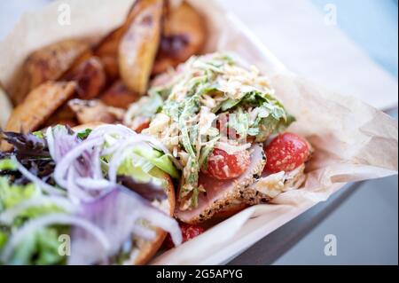 Panino di tonno asiatico con pomodori e spicchi di patate. Foto Stock