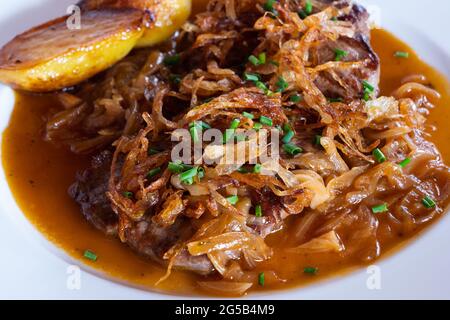 Viennese Zwiebelrostbraten, Sirloin Roast Beef con sugo di cipolla, cipolla fritta croccante e patate arrosto primo piano Foto Stock