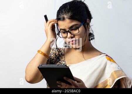 Isolato su sfondo bianco una donna indiana in ufficio in saree che lavora su tablet Foto Stock