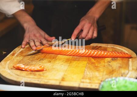 Chef taglio filetto di salmone sul tagliere di legno Foto Stock