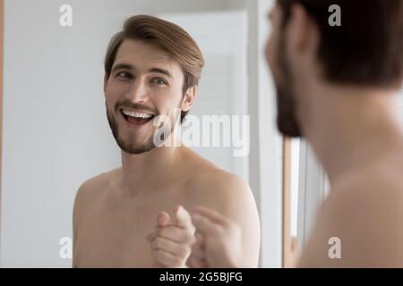 Ragazzo felice che si diverte a specchio durante le procedure di bagno giornaliere Foto Stock