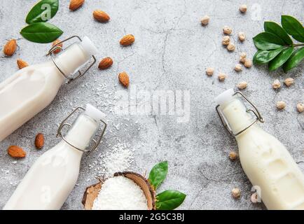 Tipi alternativi di latti vegani in bottiglie di vetro su fondo di cemento. Vista dall'alto Foto Stock