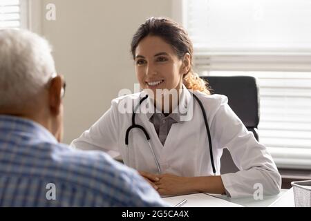 Donna sorridente medico consultare anziani paziente maschile in clinica Foto Stock