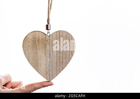 Il dito femmina tiene una decorazione a forma di cuore sullo sfondo bianco con uno spazio per la copia Foto Stock