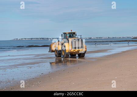 Un escavatore di costruzione prepara una spiaggia in Bretagna per l'arrivo dei turisti Foto Stock