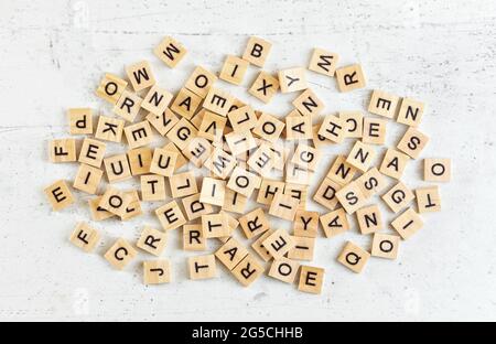 Pila di piastrelle di legno con varie lettere sparse su pietra bianca come asse, vista dall'alto Foto Stock