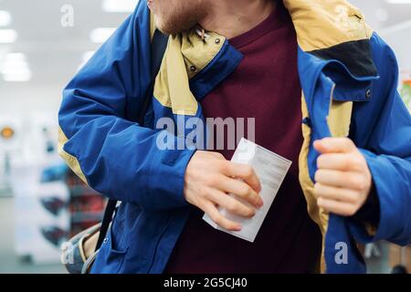 primo piano le mani del ladro del consumatore mettendo il nuovo gadget in tasca nel negozio Foto Stock