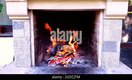 Closeup di fiamme su fuoco di log in camino con fumo e braci incandescenti. Foto Stock