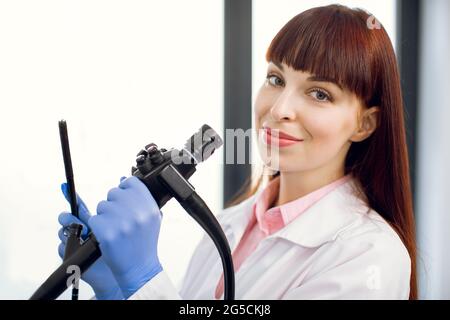 Primo piano ritratto di una giovane donna europea fidata medico posando alla fotocamera tenendo in mano il moderno endoscopio. Medicina, endoscopia, concetto di colonscopia Foto Stock