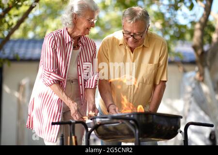 anziana coppia caucasica che fa fuoco per barbecue Foto Stock
