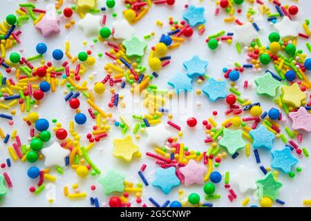 Sfondo festivo multicolore di una dispersione di caramelle zuccherate per cupcakes e altri dolci sotto forma di stelle, bastoni e palle. Colore brillante Foto Stock