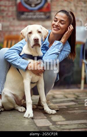 ritratto di una bella giovane donna che abbracciava e guardava il suo cane, sorridente Foto Stock