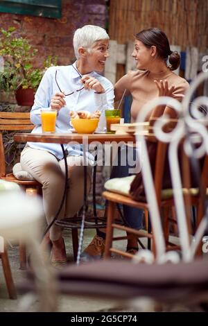 entusiasta donne, anziani e giovani, parlando, guardandosi, sorridendo. buon concetto di notizie Foto Stock