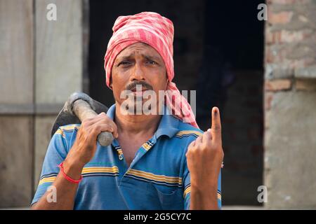 Ritratto di un agricoltore che tiene una pala con gli elettori segnati sul dito Foto Stock