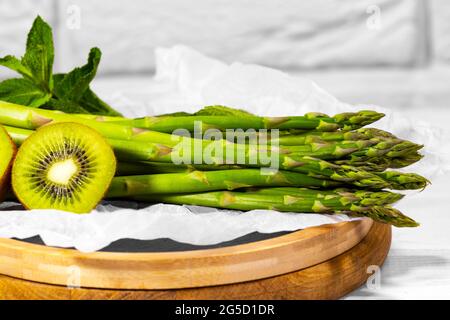 Frutta fresca Verde e verdure: kiwi, menta e asparagi su tavola di legno su sfondo bianco. Ingridiente sano per Smoothie. Cibo vegetariano Foto Stock