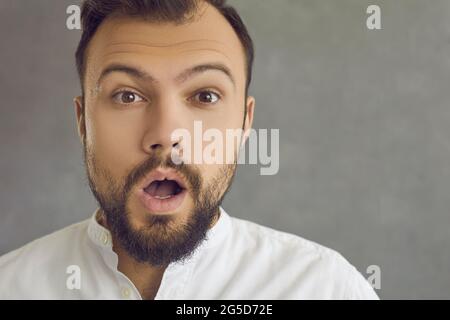 Ritratto closeup di un giovane sorpreso che guarda la macchina fotografica con un'espressione del volto scioccata Foto Stock