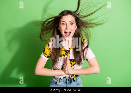 Foto di felice positivo eccitato giovane donna mani clap volare capelli isolati su sfondo verde lucido colore Foto Stock