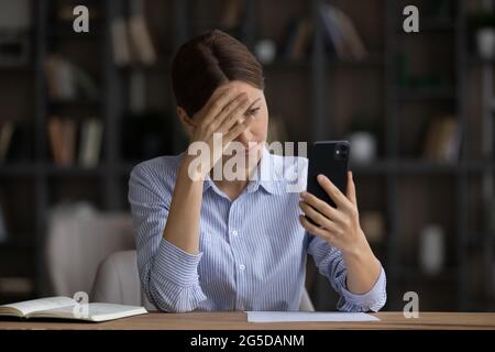 Giovane donna frustrata che ha problemi con lo smartphone. Foto Stock