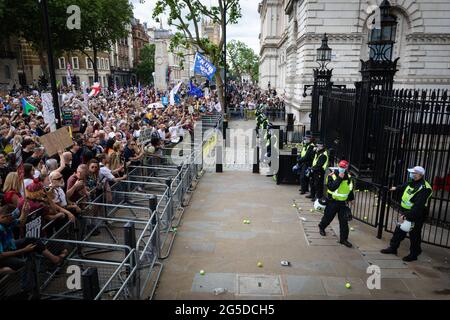 Londra, Regno Unito. 26 Giugno 2021. La polizia sta in piedi guardia, mentre i dimostranti di una dimostrazione anti-blocco gettano palle da tennis in Downing Street. Migliaia di persone hanno marciato per sollevare le loro preoccupazioni per quanto riguarda la legislazione governativa incentrata sulle vaccinazioni e la libertà di viaggiare.ÊAndy Barton/Alamy Live News Credit: Andy Barton/Alamy Live News Foto Stock