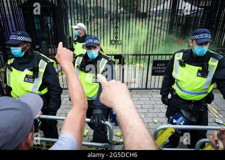 Londra, Regno Unito. 26 Giugno 2021. La polizia sta in piedi guardia mentre i dimostranti da una dimostrazione anti-blocco gettare palle da tennis e granate di fumo in Downing Street. Migliaia di persone hanno marciato per sollevare le loro preoccupazioni riguardo alla legislazione governativa incentrata sulle vaccinazioni e sulla libertà di viaggiare. Credit: Andy Barton/Alamy Live News Foto Stock