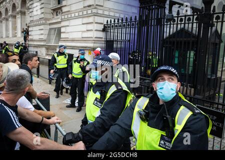 Londra, Regno Unito. 26 Giugno 2021. La polizia sta in piedi guardia mentre i dimostranti da una dimostrazione anti-blocco gettare palle da tennis e granate di fumo in Downing Street. Migliaia di persone hanno marciato per sollevare le loro preoccupazioni riguardo alla legislazione governativa incentrata sulle vaccinazioni e sulla libertà di viaggiare. Credit: Andy Barton/Alamy Live News Foto Stock