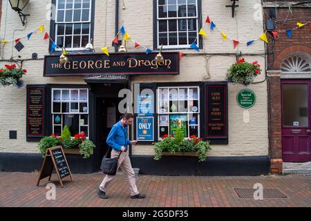 Chesham, Buckinghamshire, Regno Unito. 25 Giugno 2021. Un uomo cammina oltre i segni di allontanamento sociale fuori dal George e Dragon pub. Il centro di Chesham era tranquillo questo pomeriggio. Il tasso di casi positivi di Covid-19 per 100,000, tuttavia, è aumentato in Chilterns a 70.9, (68) per la settimana che termina il 21 giugno dal 39.6, (38) dalla settimana prima . Credito: Maureen McLean/Alamy Foto Stock