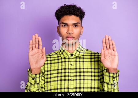 Ritratto di bel ragazzo serio che mostra due palme ignorare rinunciare isolato su sfondo viola colore viola Foto Stock