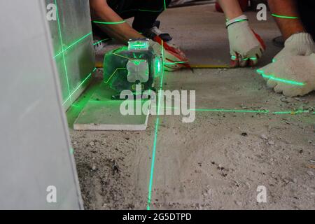 l'allestitore misura le linee di riparazione utilizzando una livella laser verde, Foto Stock