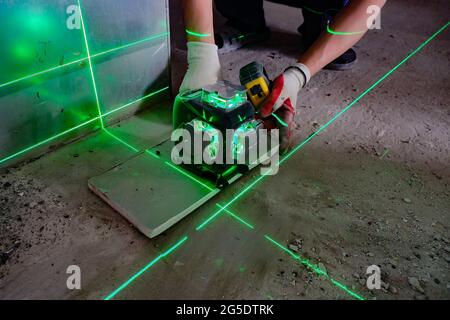 l'allestitore misura le linee di riparazione utilizzando una livella laser verde, Foto Stock