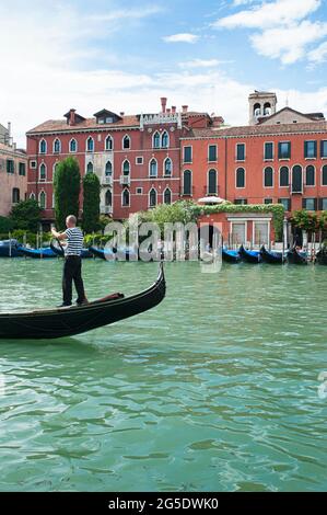 Immagine verticale del Canal Grande nei pressi del Ponte di Rialto con gondoliere che punisce la gondola attraverso le verdi acque del canale, Venezia, Italia Foto Stock