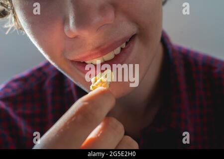 primo piano giovane maschio che tiene popcorn per metterlo in bocca Foto Stock