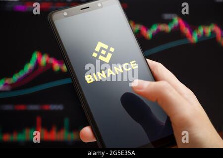 Ucraina, Odessa - 1 giugno 2021: Primo piano della mano che tiene smartphone con l'app mobile Binance in esecuzione sullo schermo con grafico di trading in background Foto Stock