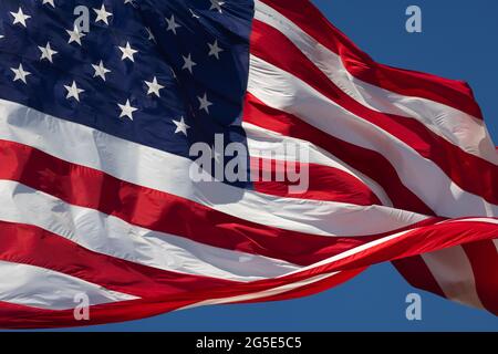 Bandiera americana che oscilla nel vento contro un cielo blu profondo. Foto Stock