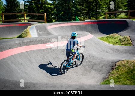 Un bambino corre in bicicletta sulla nuova pista da pompa BMX South Glenmore Park in una serata estiva a Calgary Alberta Canada. Foto Stock