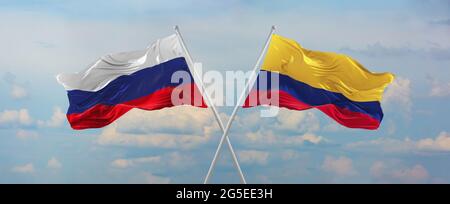 Bandiere della Russia e della Colombia che sventolano nel vento su flagpoli contro il cielo con le nuvole nella giornata di sole. Simboleggiando la relazione, dialogo tra due countr Foto Stock