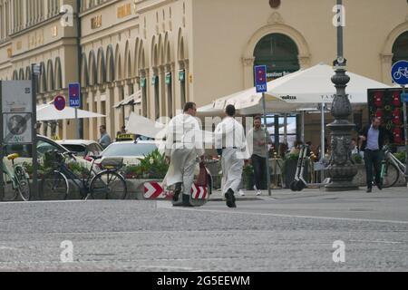 Due servitori d'altare hanno lasciato la chiesa e stanno attraversando l'Odeonsplatz Monaco, discutendo tra loro. Foto Stock