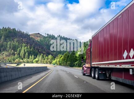 Classic burgundy cofano potente grande carro di perforazione lungo raggio industriale semi-camion trasporto di carichi commerciali in furgone secco semi-rimorchio in salita Foto Stock