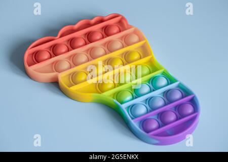 Giocattoli colorati anti-stress sensoriale pop in forma di piedi su sfondo blu. Foto Stock