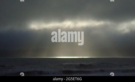 Pioggia condimenti sfocati con un cerotto di sole sulla costa di Kapiti, Nuova Zelanda Foto Stock