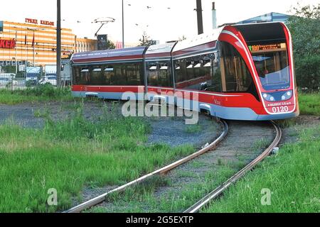 Un tram moderno e tranquillo si muove attraverso le strade della metropoli sullo sfondo dei centri commerciali. San Pietroburgo. Russia. Giugno 25 2021 Foto Stock