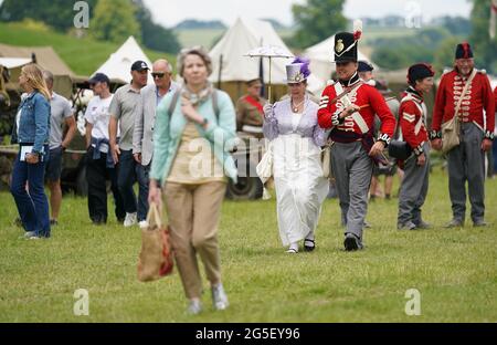 Due interpreti di storia vivente camminano attraverso la folla durante il festival di storia della valle del Chalke a Broad Chalke, vicino Salisbury, Wiltshire. Data immagine: Sabato 26 giugno 2021. Foto Stock