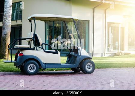 Attività ricreative all'aperto. Un golf cart bianco è parcheggiato vicino alla casa cottage moderna. Auto elettrica nel parcheggio dell'area del resort Foto Stock